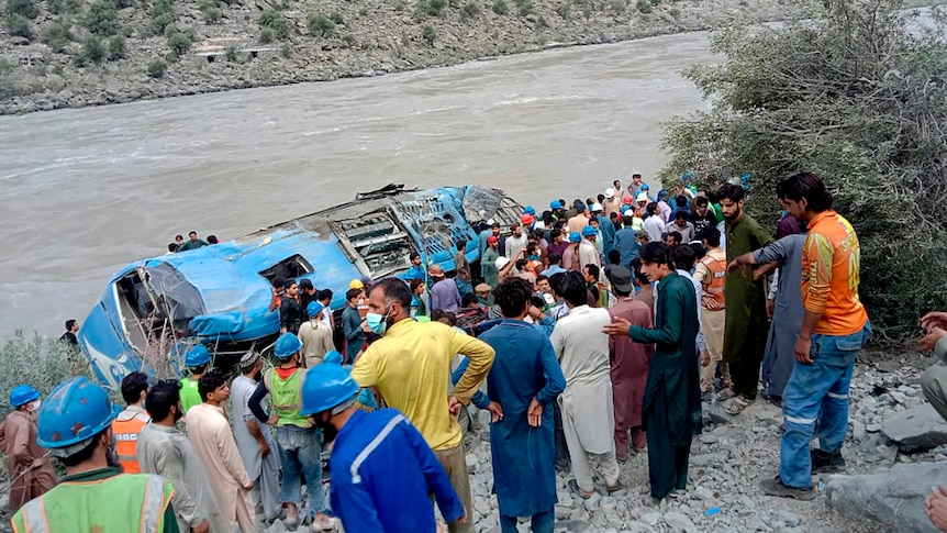 Locals gather around a bus that rolled down a ravine after an explosion in a remote province of Pakistan.