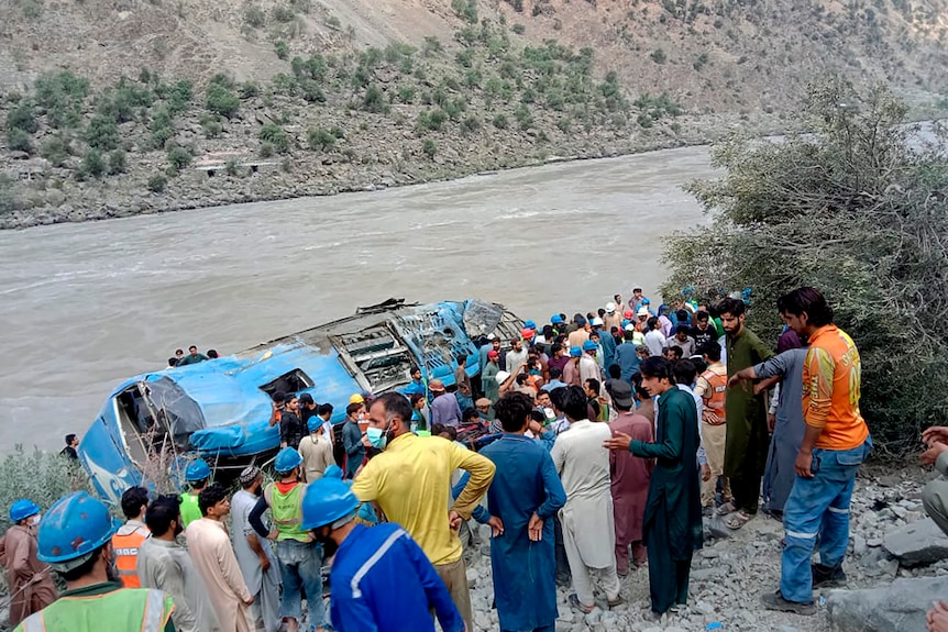 Locals gather around a bus that rolled down a ravine after an explosion in a remote province of Pakistan.