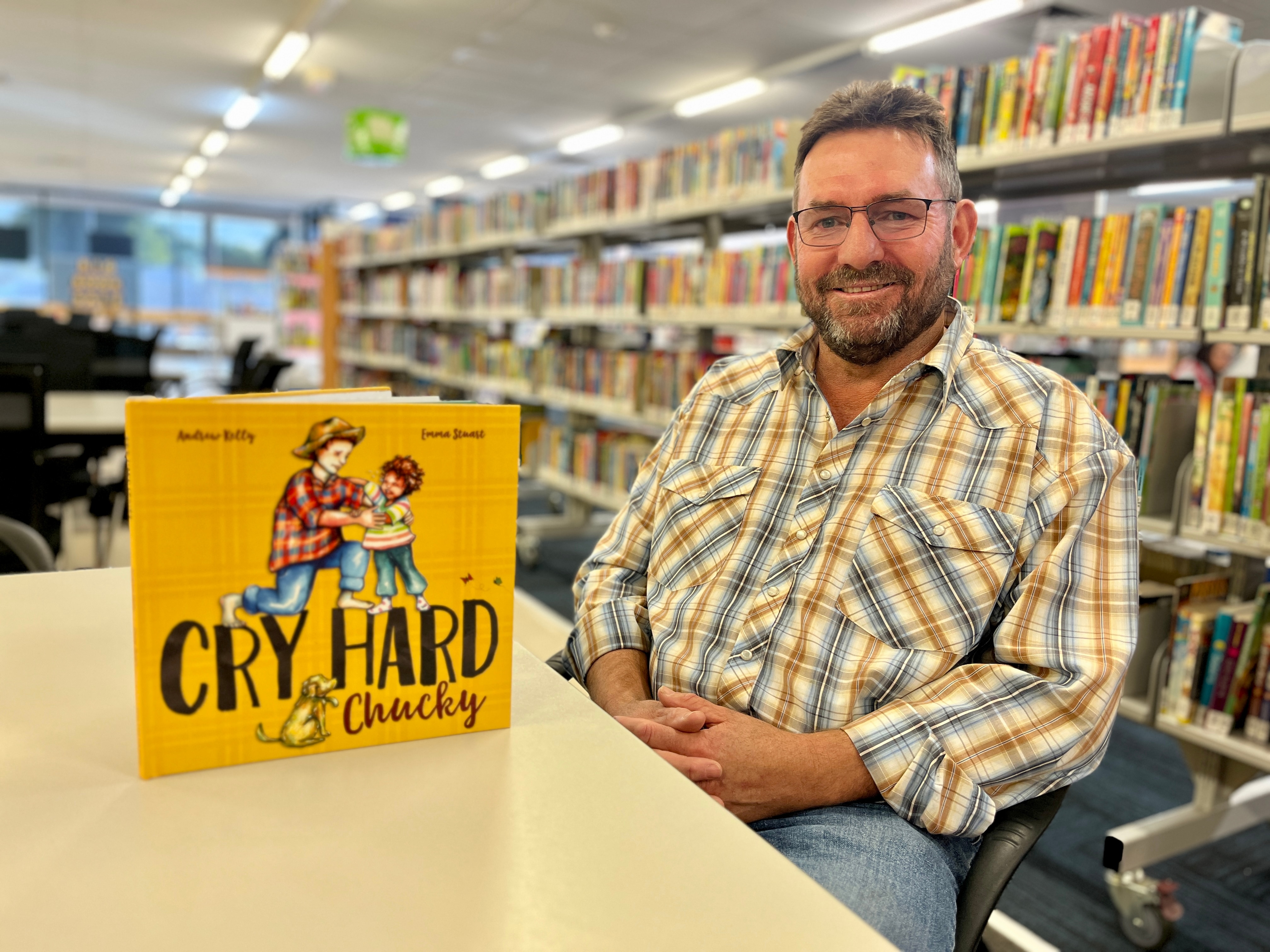 A children's book on a table next to a man looking happy.