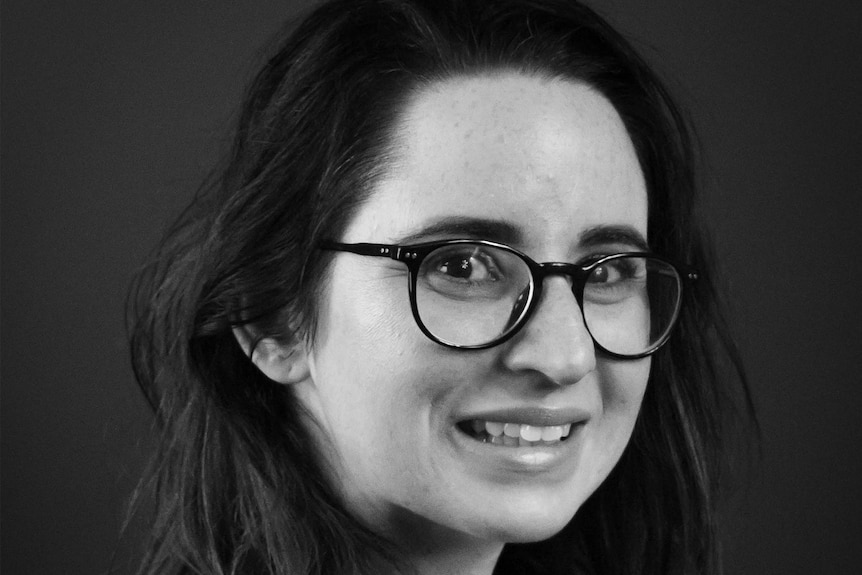 A black and white photo of a young woman wearing black framed glasses