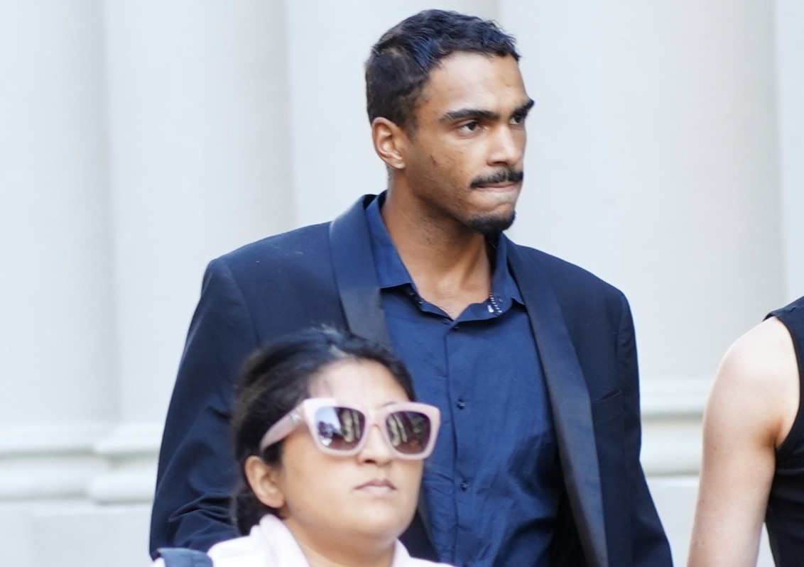 Roosevelt Williams Jr usa terno enquanto caminha pela rua. 