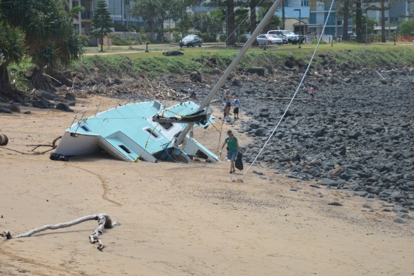 A Bargara Beach Army volunteer in action next to a wrecked yacht.