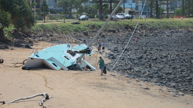 A Bargara Beach Army volunteer in action next to a wrecked yacht.