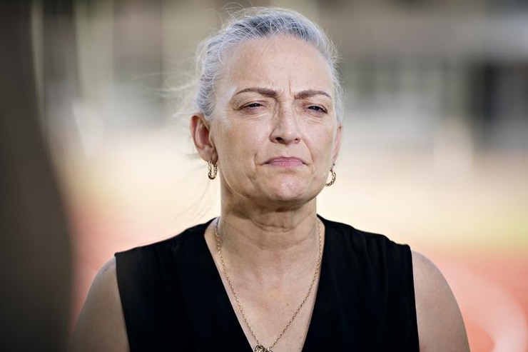 A woman wearing a black top looks towards the camera.