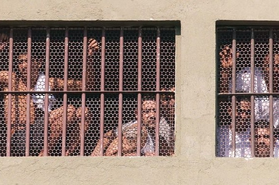 Several men behind large iron bars.