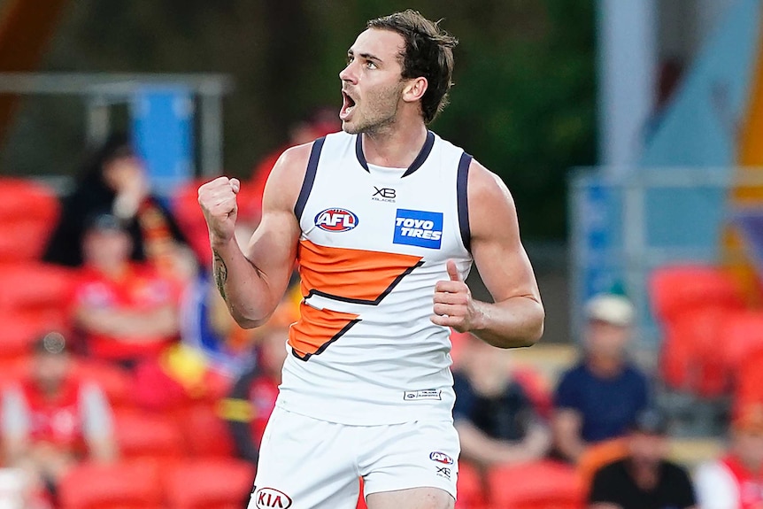 An GWS Giants AFL player pumps his right fist as he celebrates a goal against the Gold Coast Suns in Carrara.
