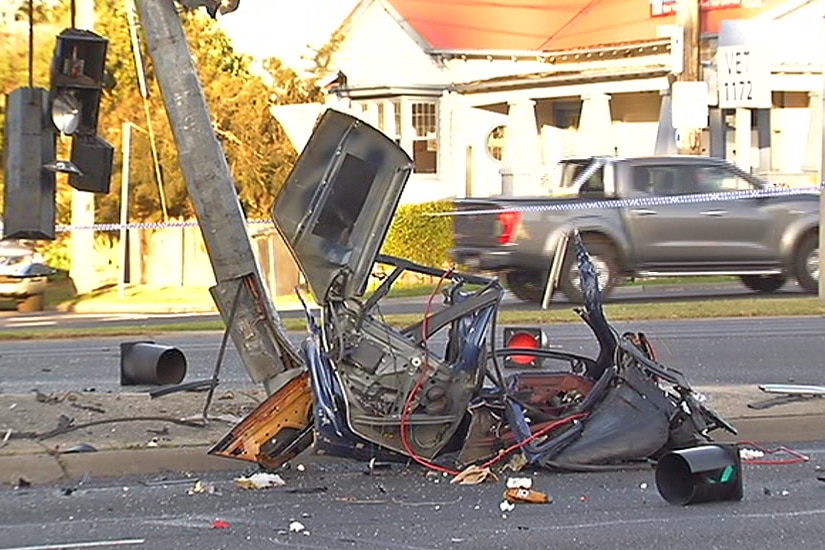 Car wrekage is shown on the road alongside a bent pole.