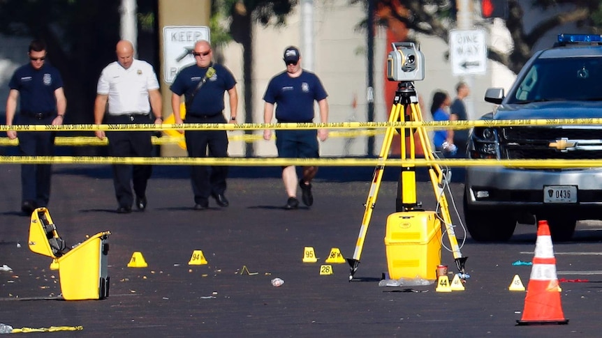 Evidence markers rest on the street behind police tape at the scene of a mass shooting.