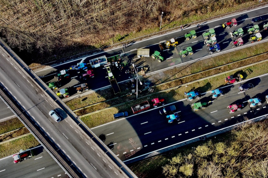 A view from above as a group of tractors cover two sections of highway.