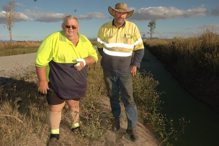 Crocodile bite victim  Daryl Bell and Bruce Craven stand next to an irrigation channel.