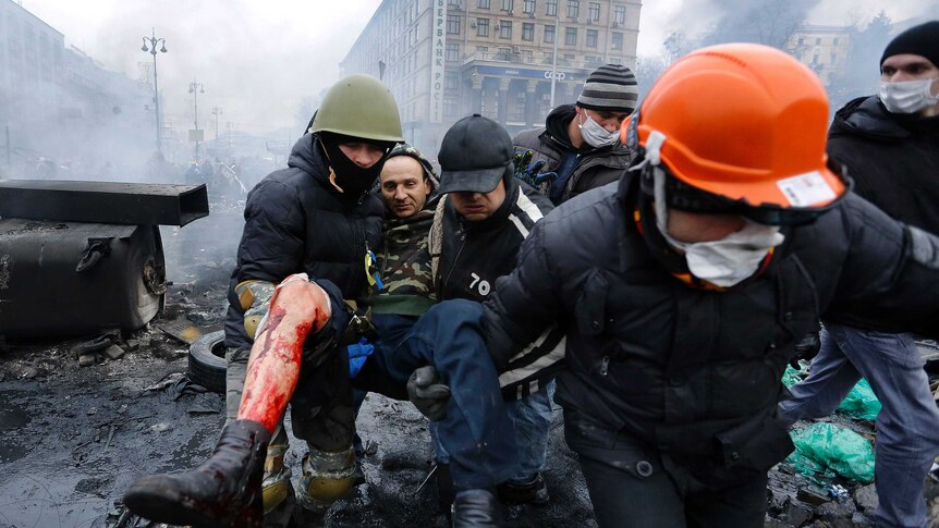 Ukraine anti-government protesters carry a man with a bullet wound to his leg.