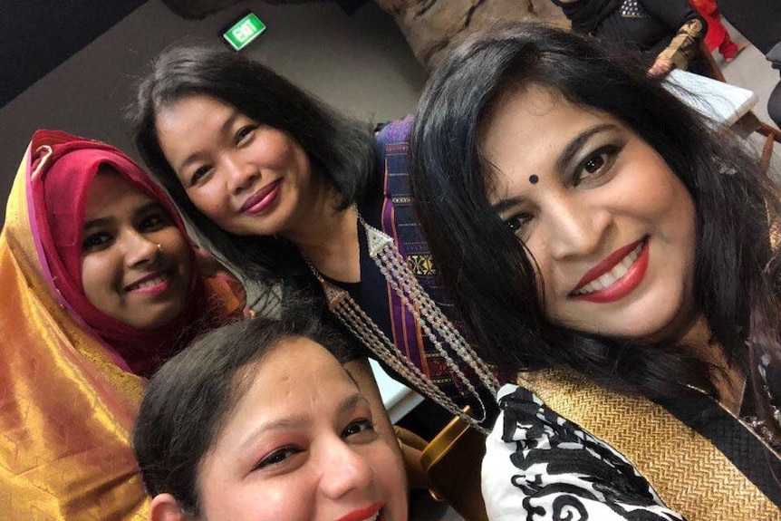 Four women smile at the camera.