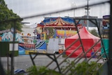Ekka rides being packed up, image taken through a wire fence.