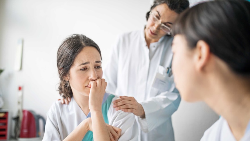 Two health practitioners counsel a young teenage girl