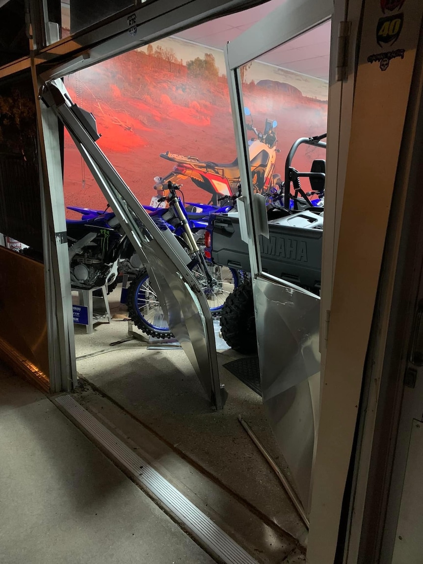 Twisted door frame and hanging off hinges with glimpses of blue motorcycles in background