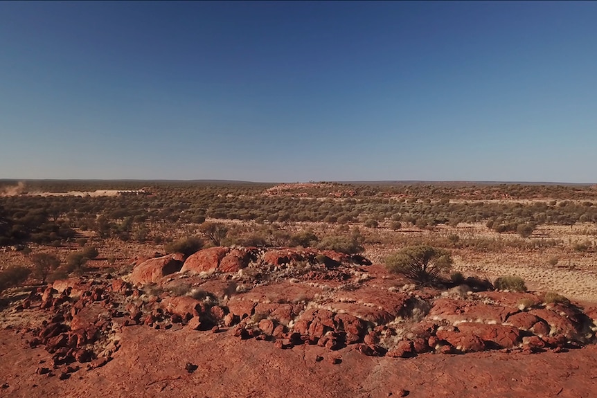 Bird's-eye view of rocky desert landscape in the outskirts of Mimili on a cloudless blue sky day.