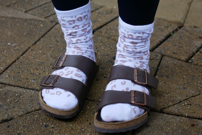 A woman wearing a pair of leopard print socks with her sandals 