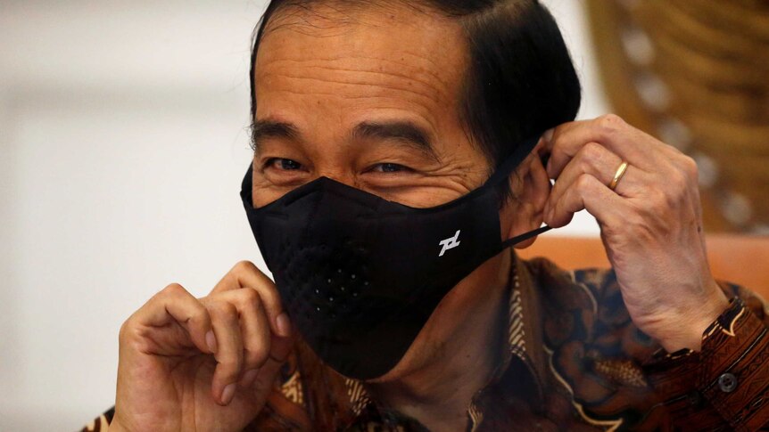 The Indonesian president smiles as he begins to take off his face mask.