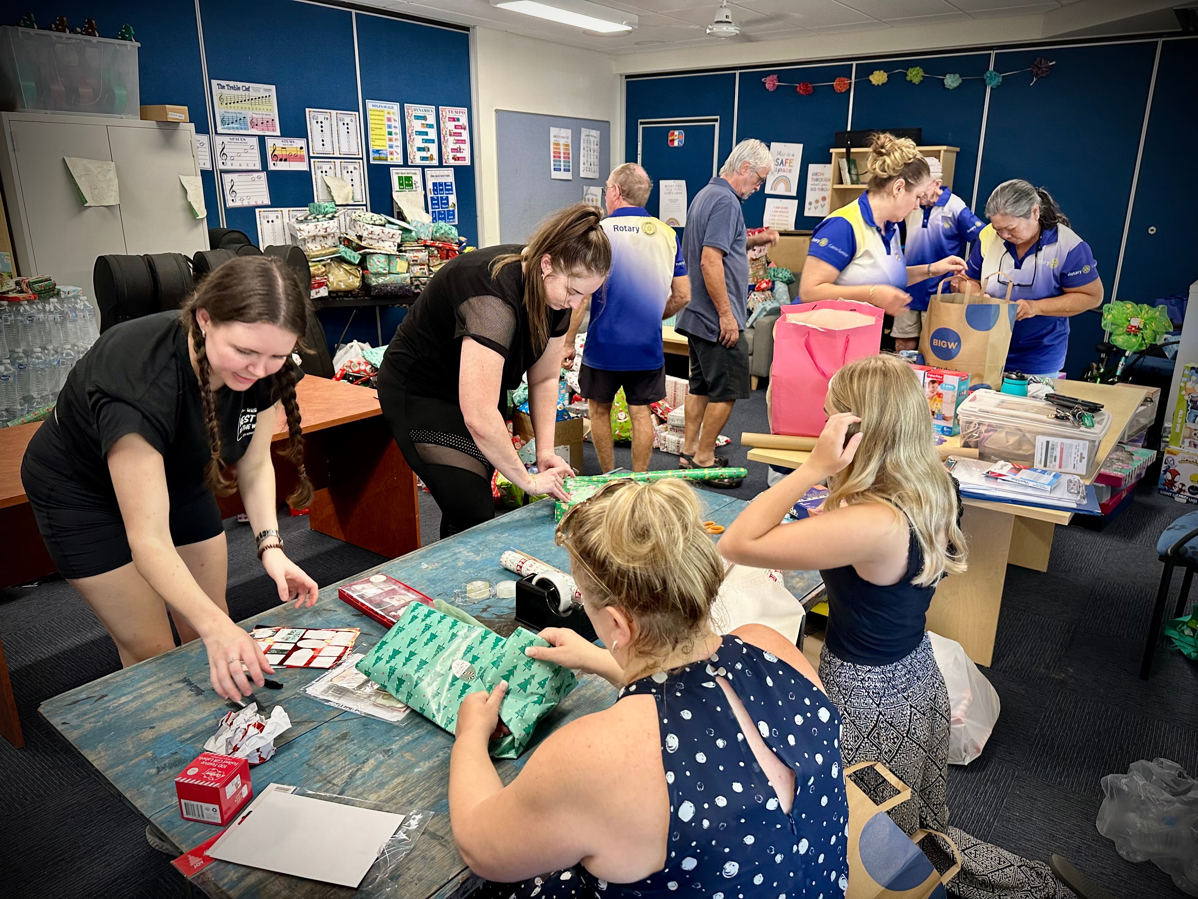 A group of people in a room working to wrap presents
