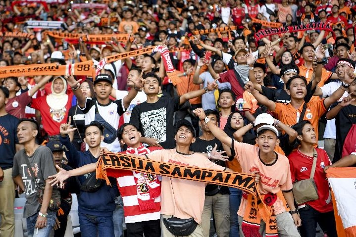 Lautan klub penggemar sepak bola memegang syal dengan tulisan di atasnya "Persija sampai mati".