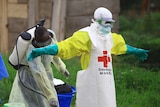 A doctor wearing heavy protective gear is being hosed down.