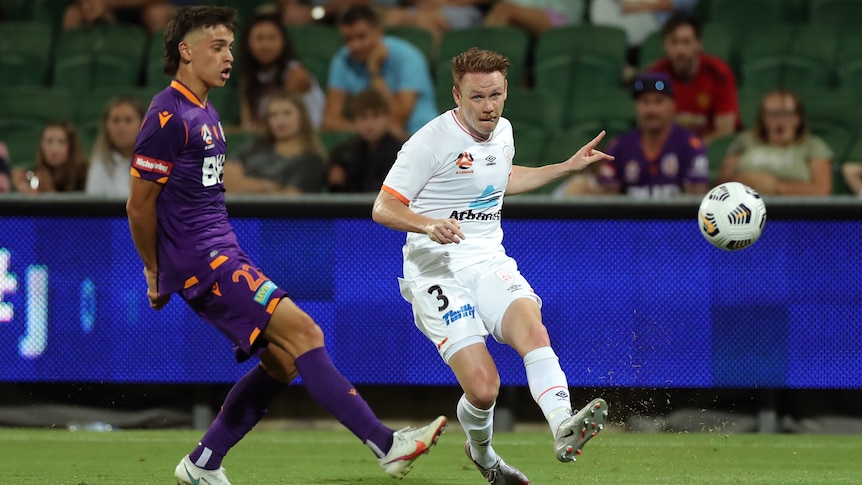 An A-League footballer sidefoots the ball forward towards teammates as a defender tries to close him down. 