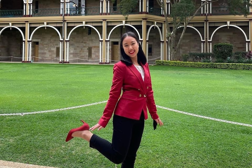 A young woman in red suit is posing to the camera 