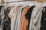 Clothing hung on white hangers on a metal rack.