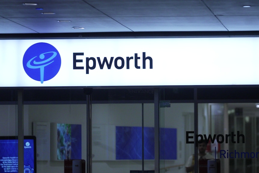 An unidentified man leaving a building with a sign saying 'Epworth' at night
