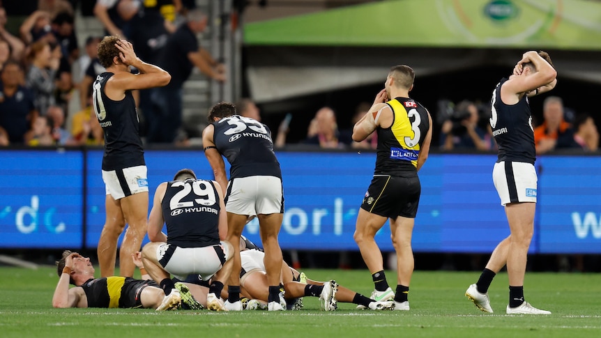 Richmond and Carlton players look disappointed and tired at the final siren