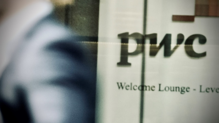 A person walks past the PwC welcome sign inside a building.