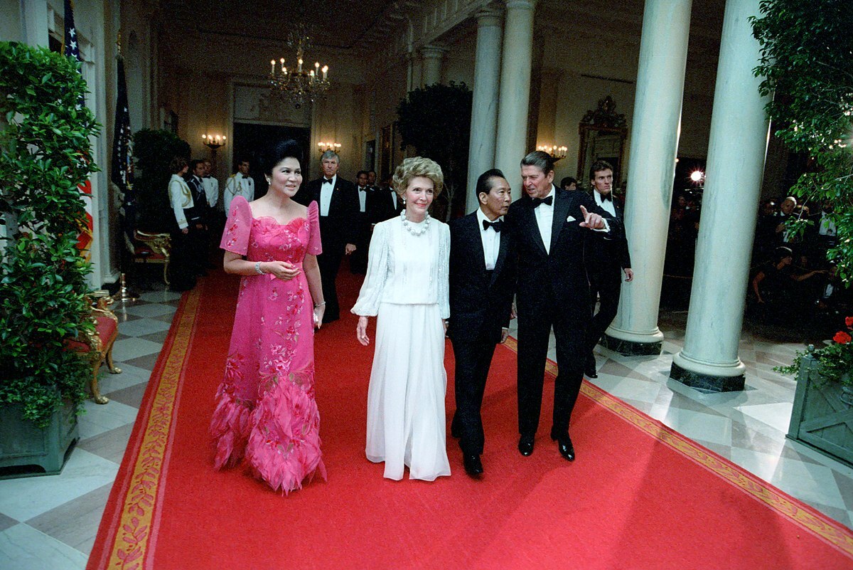Imelda Marcos in a bright pink ballgown with feathered skirt, Nancy Reagan in a chic white gown, presidents both in tuxedos