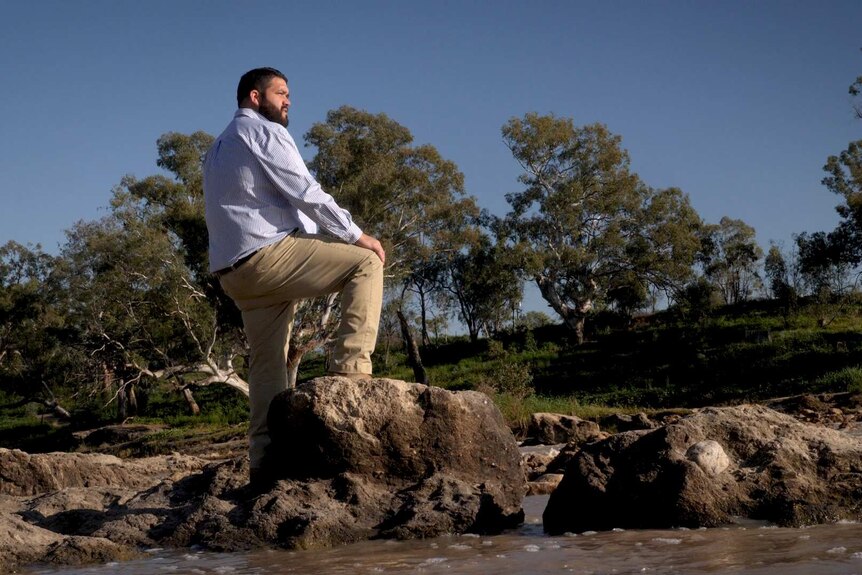 A man stand on rocks in the Darling River at Brewarrina