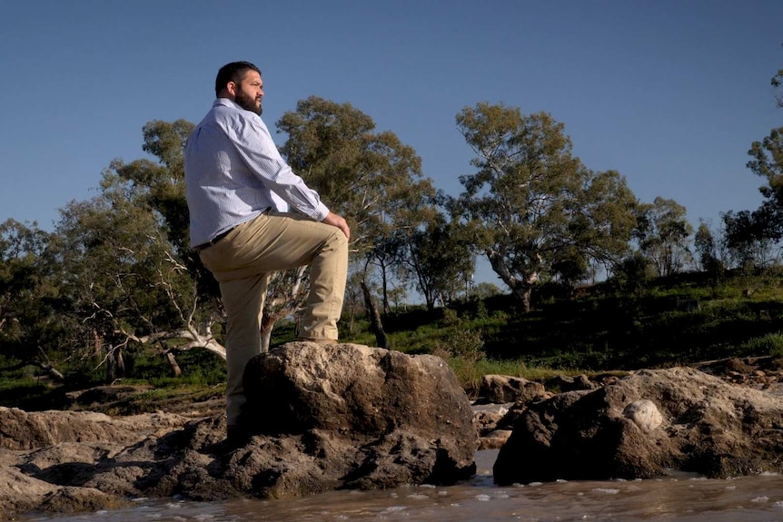 A man stand on rocks in the Darling River at Brewarrina