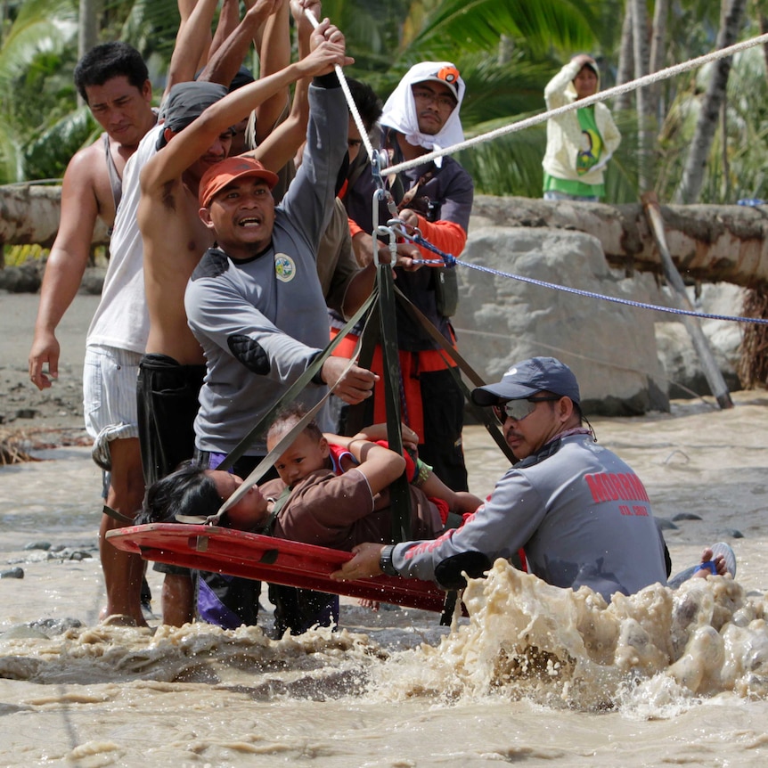Rescuers evacuate a pregnant woman with her child after surviving flooding in New Bataan town, in the Philippines.