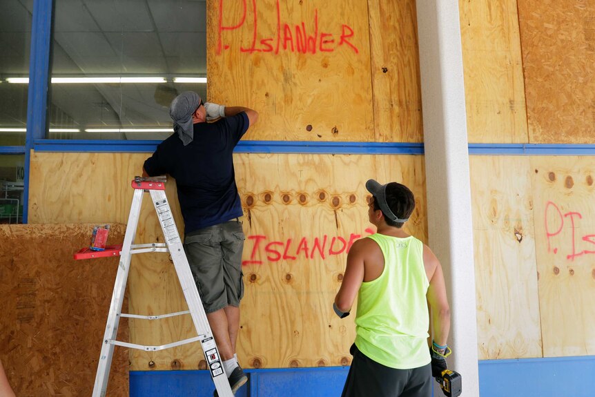 Workers board up the windows of a store.