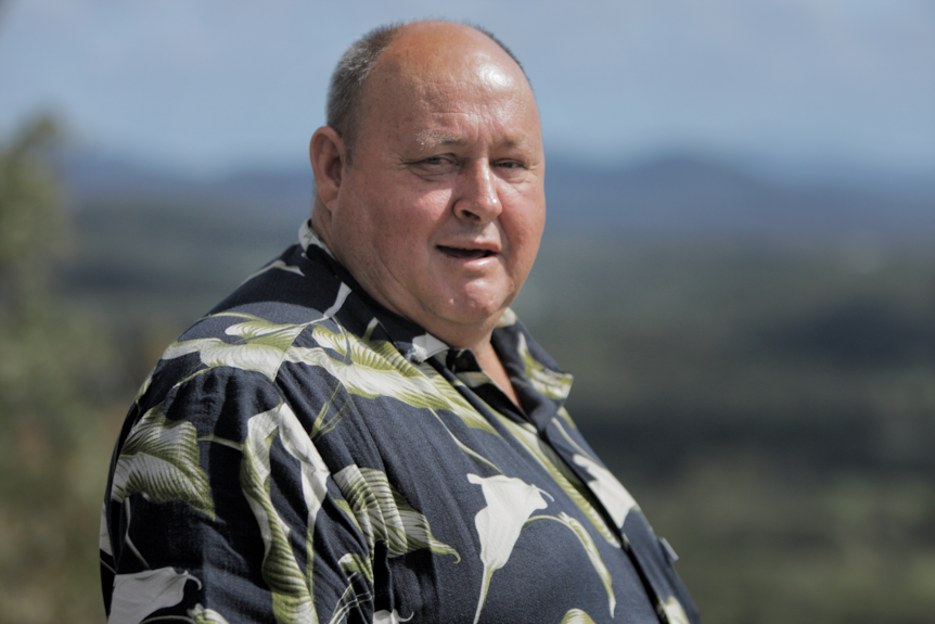 Man wearing a black printed shirt standing outside.