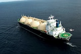 An overhead view of an LNG tanker off the WA coast with a helicopter hovering above its helipad.