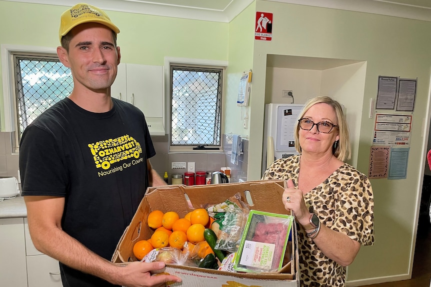 A man and woman hold a box of food 