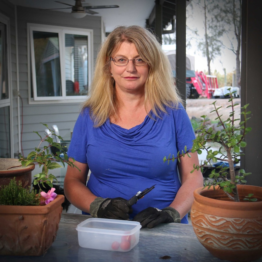Liz Westwood, wearing gardening gloves and holding secateurs, smiles while looking directly at the camera.