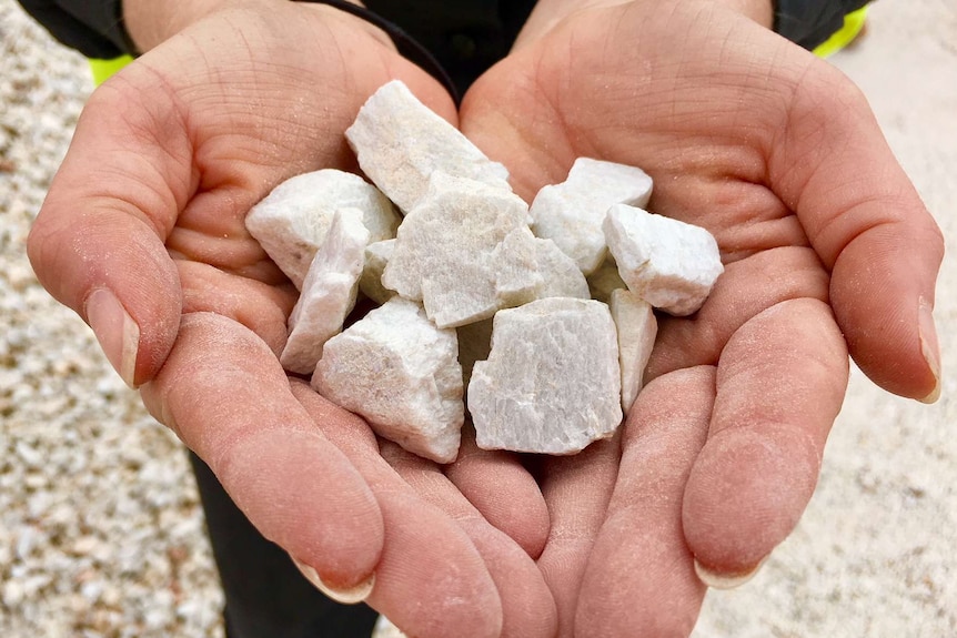 Close up of women's hands holding small white rocks