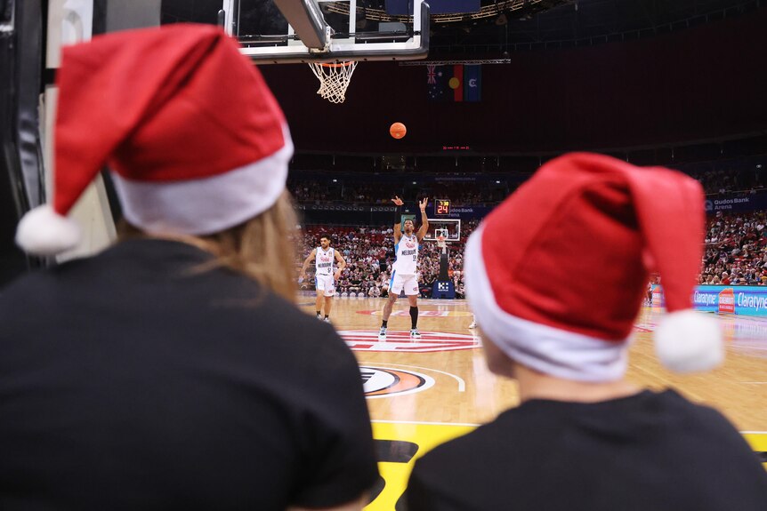 Fans wearing Christmas hats watch a basketball game