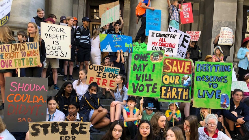 Dozens of young people gathered together, holding colourful signs with pro-climate action slogans.
