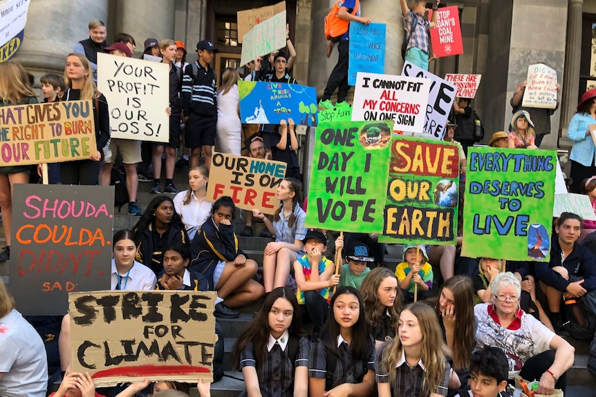 Dozens of young people gathered together, holding colourful signs with pro-climate action slogans.