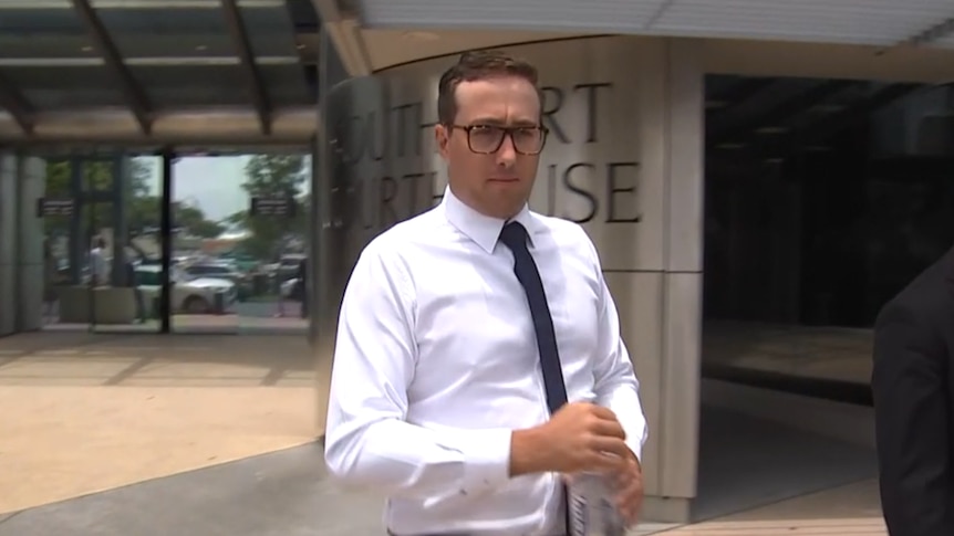 a man in a white button-up shirt and black tie walking out of a courthouse