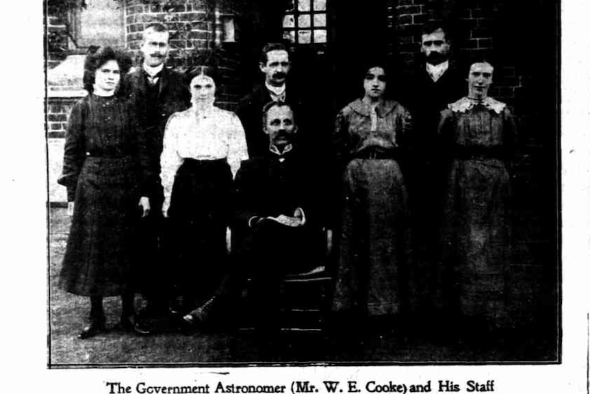 Black and white newspaper photograph showing several men and women, with the title 'The Government Astronomer and His Staff'
