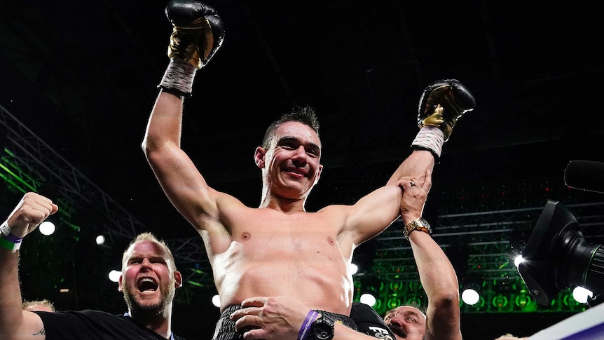 Boxer Tim Tszyu holds his gloved hands up while being carried by his team after beating Jeff Horn.