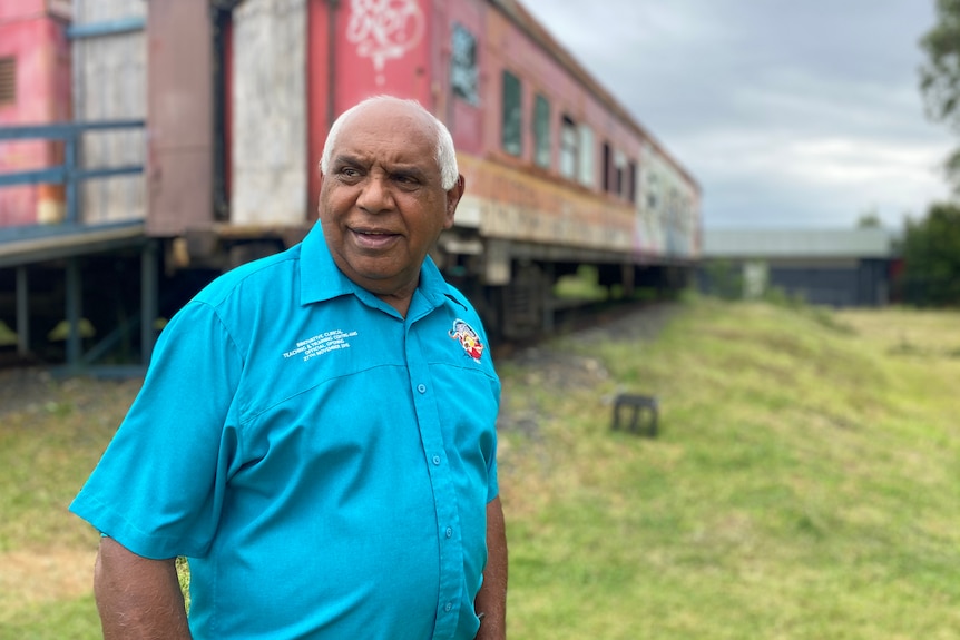 an elderly man standing outdoors looking