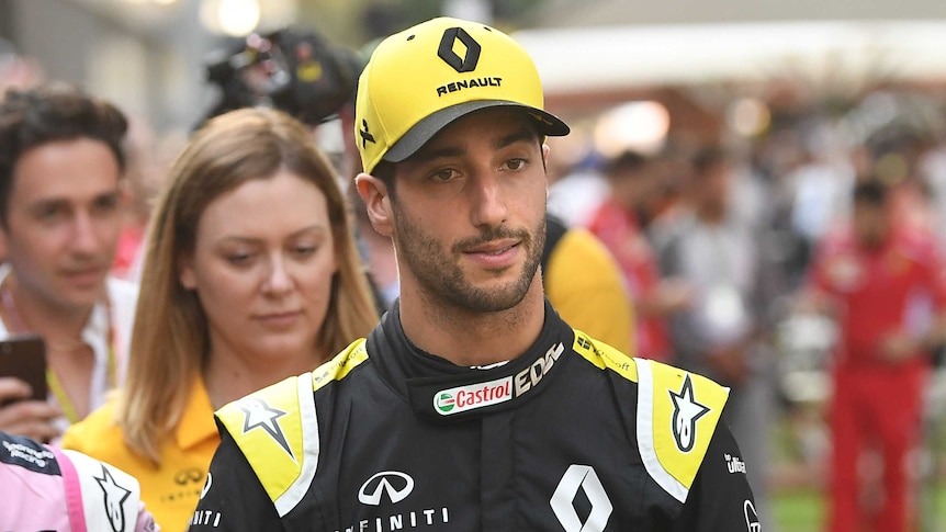 Daniel Ricciardo has a neutral expression on his face wearing a yellow Renault cap