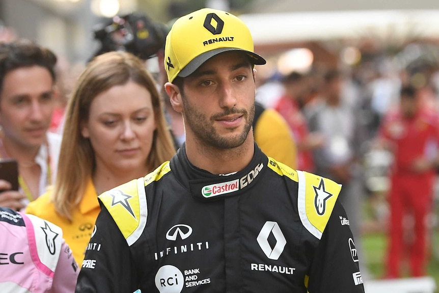 Daniel Ricciardo has a neutral expression on his face wearing a yellow Renault cap